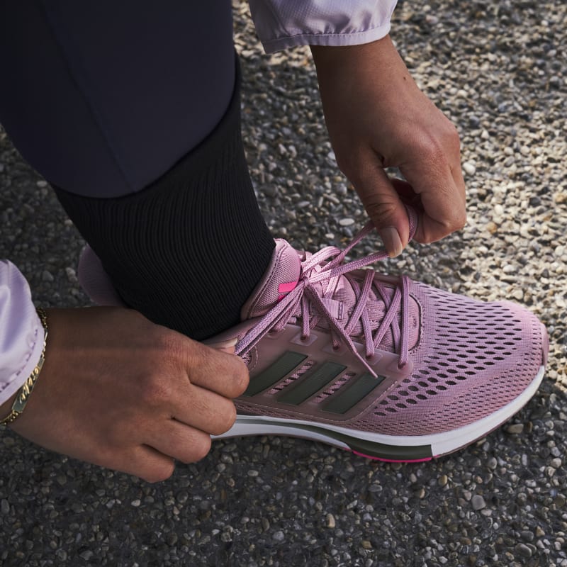 נעלי ריצה לנשים Adidas EQ21 Run GZ4075 על רגלי הספורטאית שורכת שרוכים ברגל ימין זום רק על הרגל